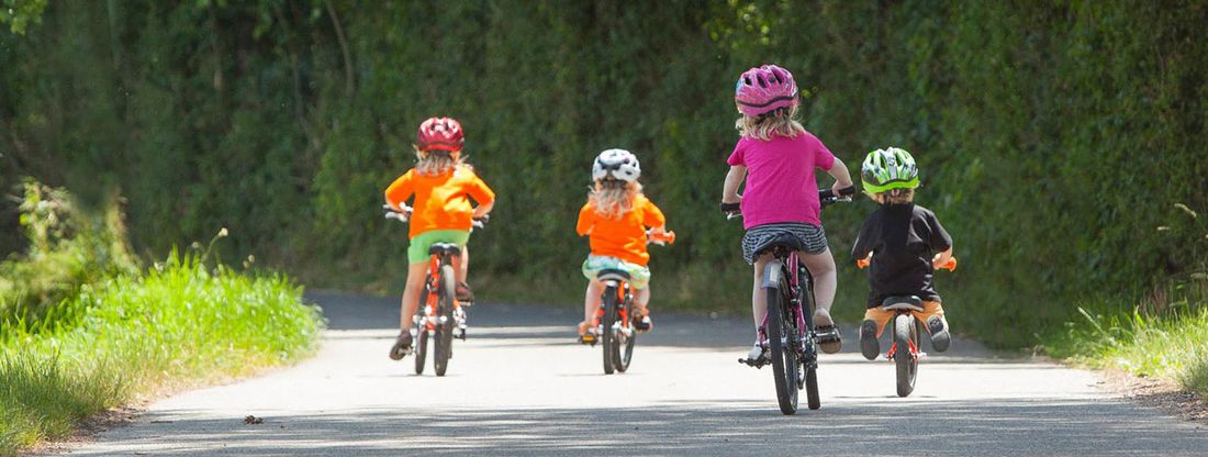 Vier Kinder mit Laufrad und Kinderfahrrad unterwegs